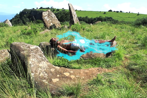 Person lays in a green grassy area with a light blue, ghost like halo over their body.