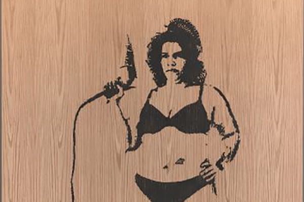 Black ink print of a female figure holding a power tool printed on wood surface.