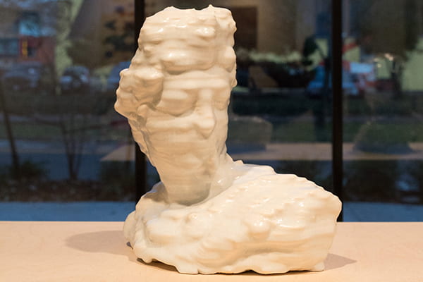 3-D printed sculpture of a bust sits on a wood tabletop.