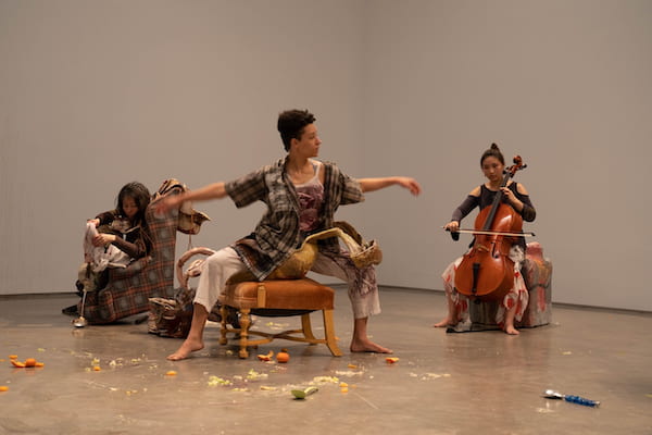 Three performers in white gallery space.