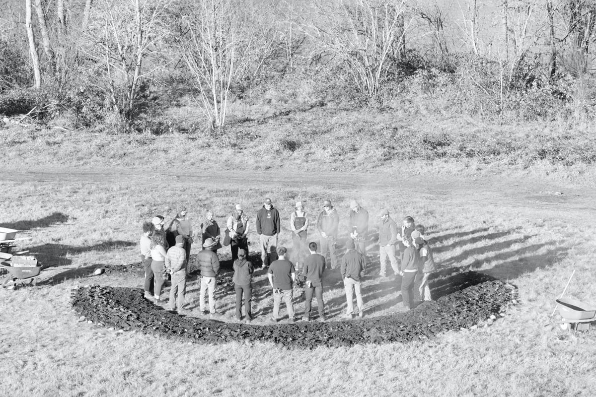 Group of people standing in a circle in an outdoor field.
